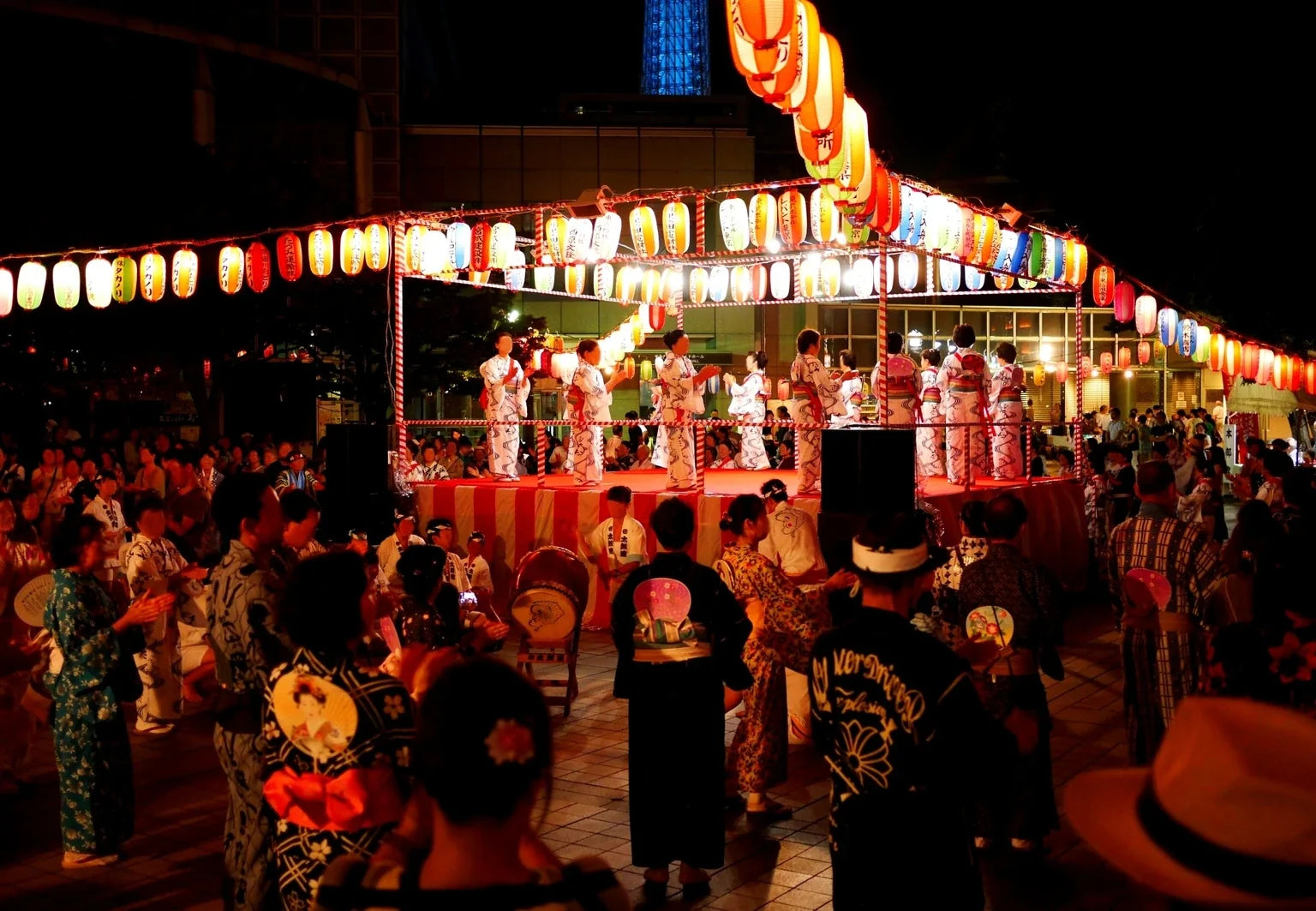 A lively Japanese summer festival with glowing lanterns, yukata, and stage performances in Japan, featured in the ONSENSUI99 cultural story.