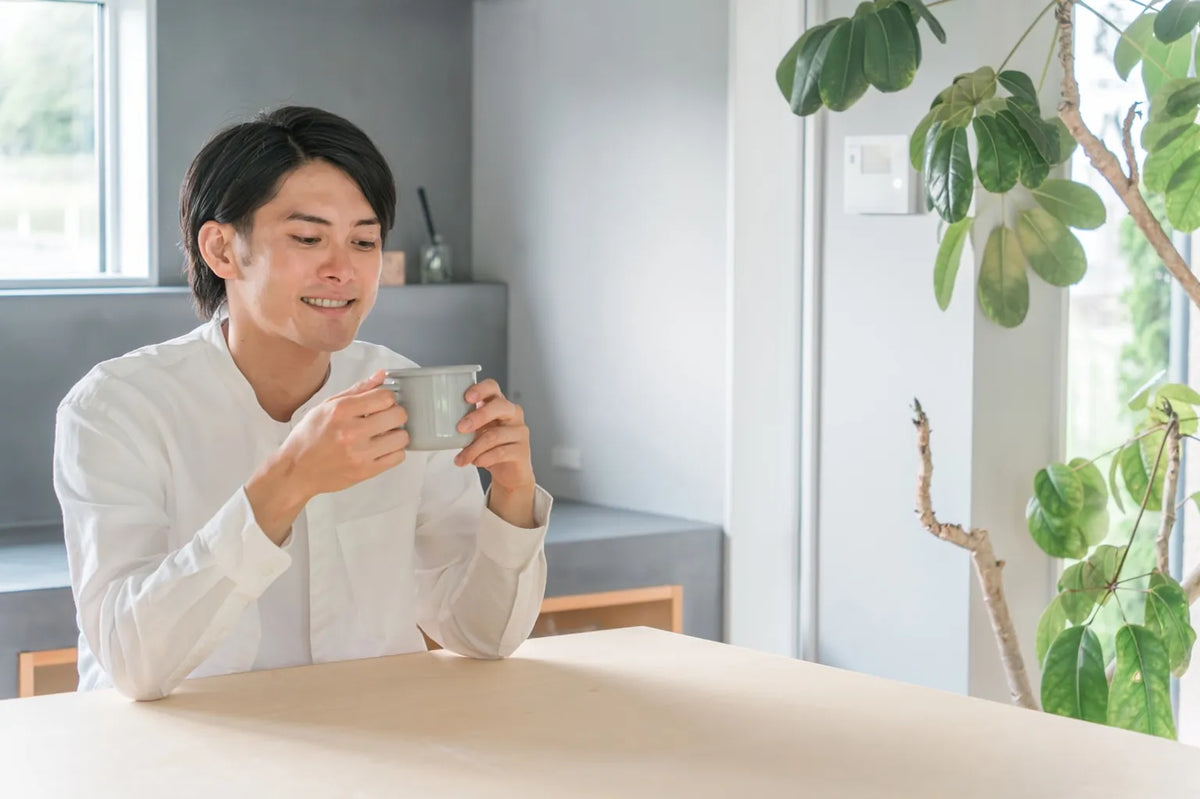 Japanese man enjoying a relaxing moment with soft water, expressing the smooth taste of ONSENSUI99 in daily life.