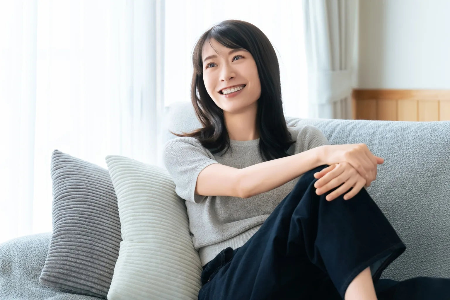 Japanese woman relaxing on a sofa in a bright condominium living room in Thailand