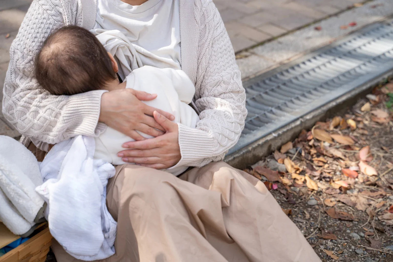 A mother holding her baby outdoors, expressing comfort, bonding, and trust in a Japanese family lifestyle.