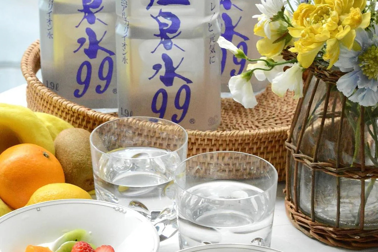 A bright breakfast table with ONSENSUI 99 bottles, yogurt, fruits, and clear glasses of water