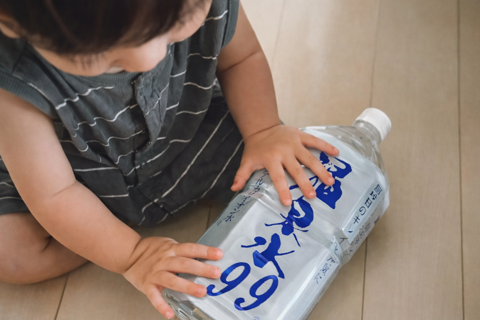 小さな女の子が温泉水99の空きボトルをきれいにたたんでリサイクルする様子