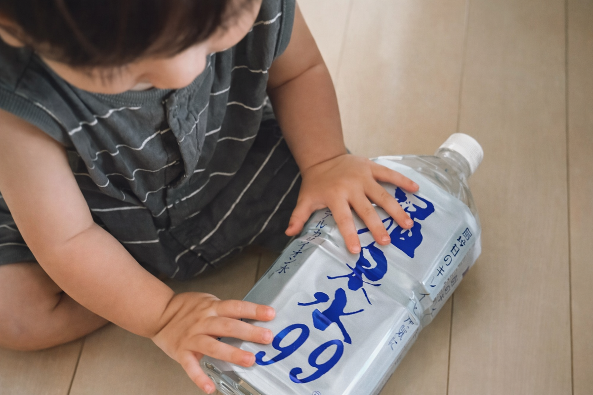 小さな女の子が温泉水99の空きボトルをきれいにたたんでリサイクルする様子