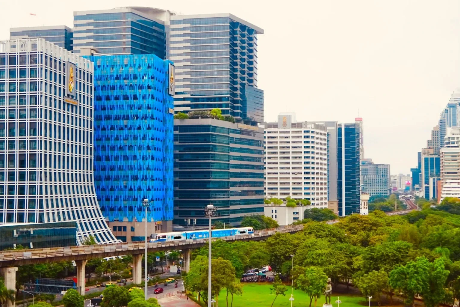 Bangkok cityscape view with modern buildings, BTS skytrain, and green park area in Thailand