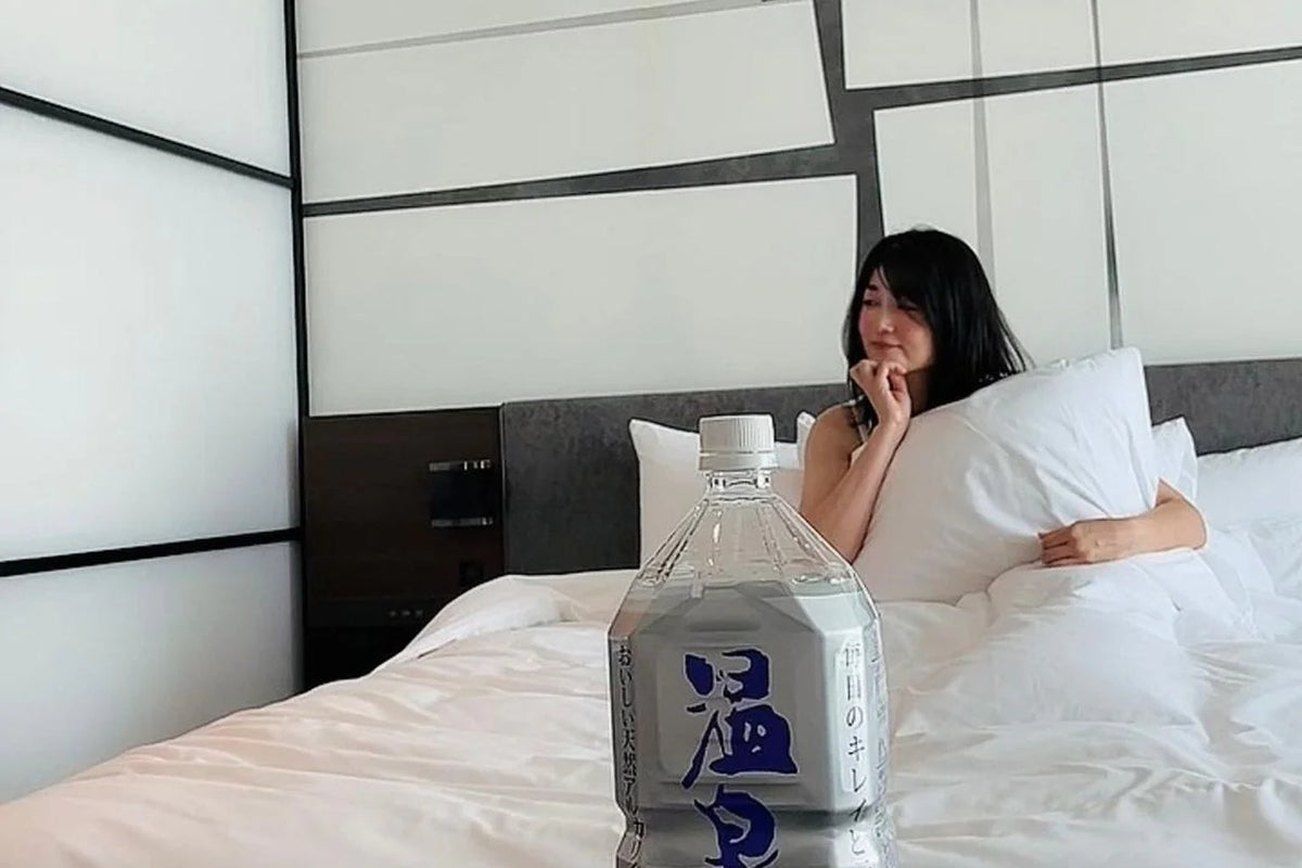タイ旅行中にホテルで温泉水99を飲む女性|安全な水で体調を整える新しい旅の習慣