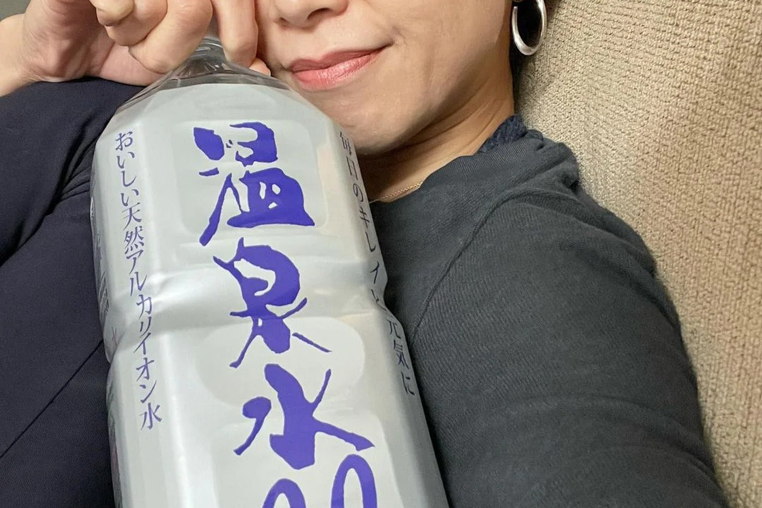 Woman holding Onsensui99 natural alkaline water bottle for daily hydration