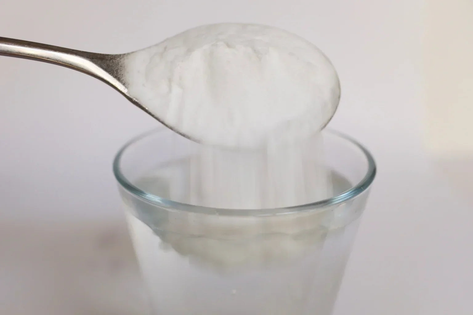 Protein powder being added to liquid in a shaker, showing texture and mixing issues that affect taste.