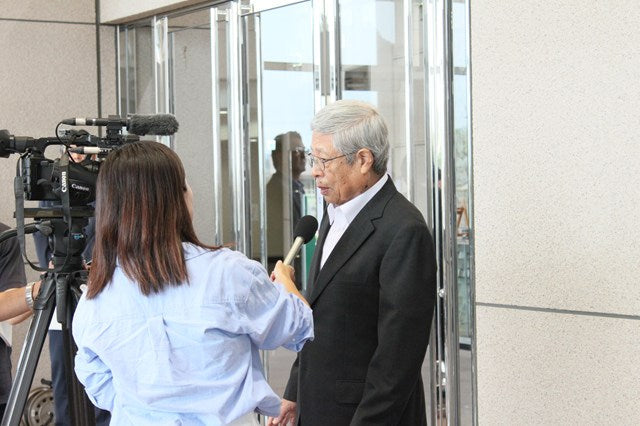 温泉水99を手がけるエスオーシー株式会社の草間社長が、KTS鹿児島テレビのレポーターからインタビューを受けている様子