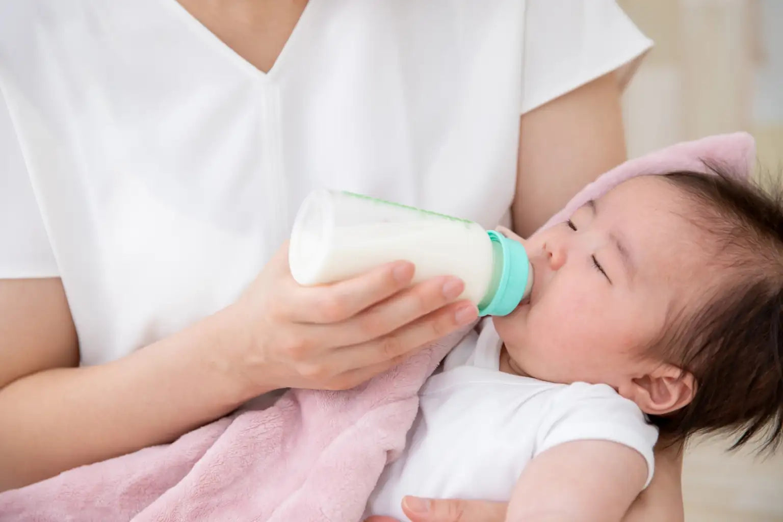 A sleeping baby being fed from a bottle, expressing comfort and gentle soft water support for daily family care.