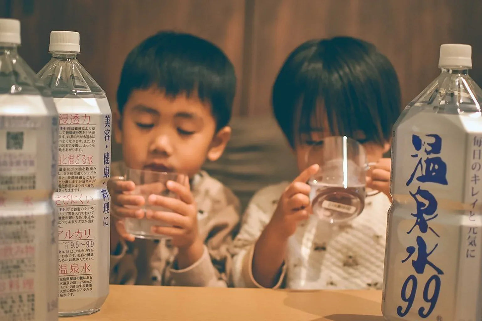 Children drinking water at table with ONSENSUI99 bottles for family hydration