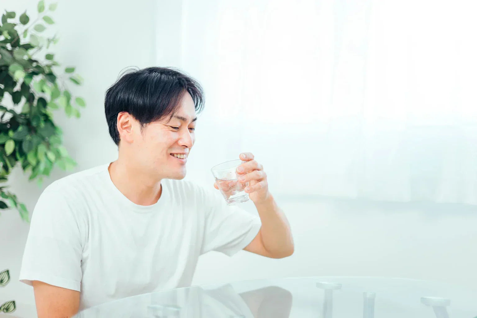 Japanese man drinking soft water with a smile, expressing the smooth and refreshing feel of ONSENSUI99.
