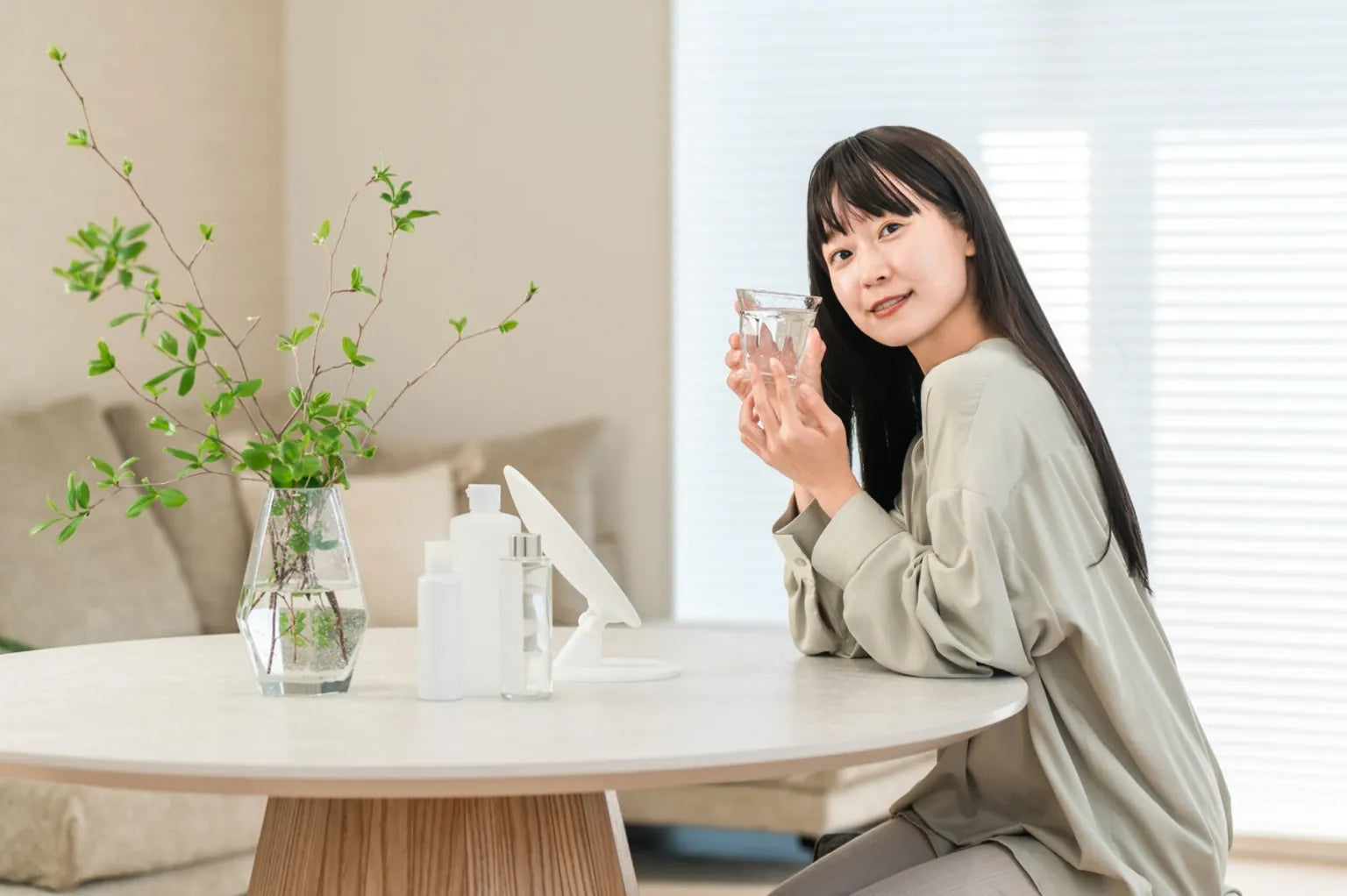 Japanese woman drinking water at home, showing a calm lifestyle with soft water and premium ONSENSUI99 hydration.