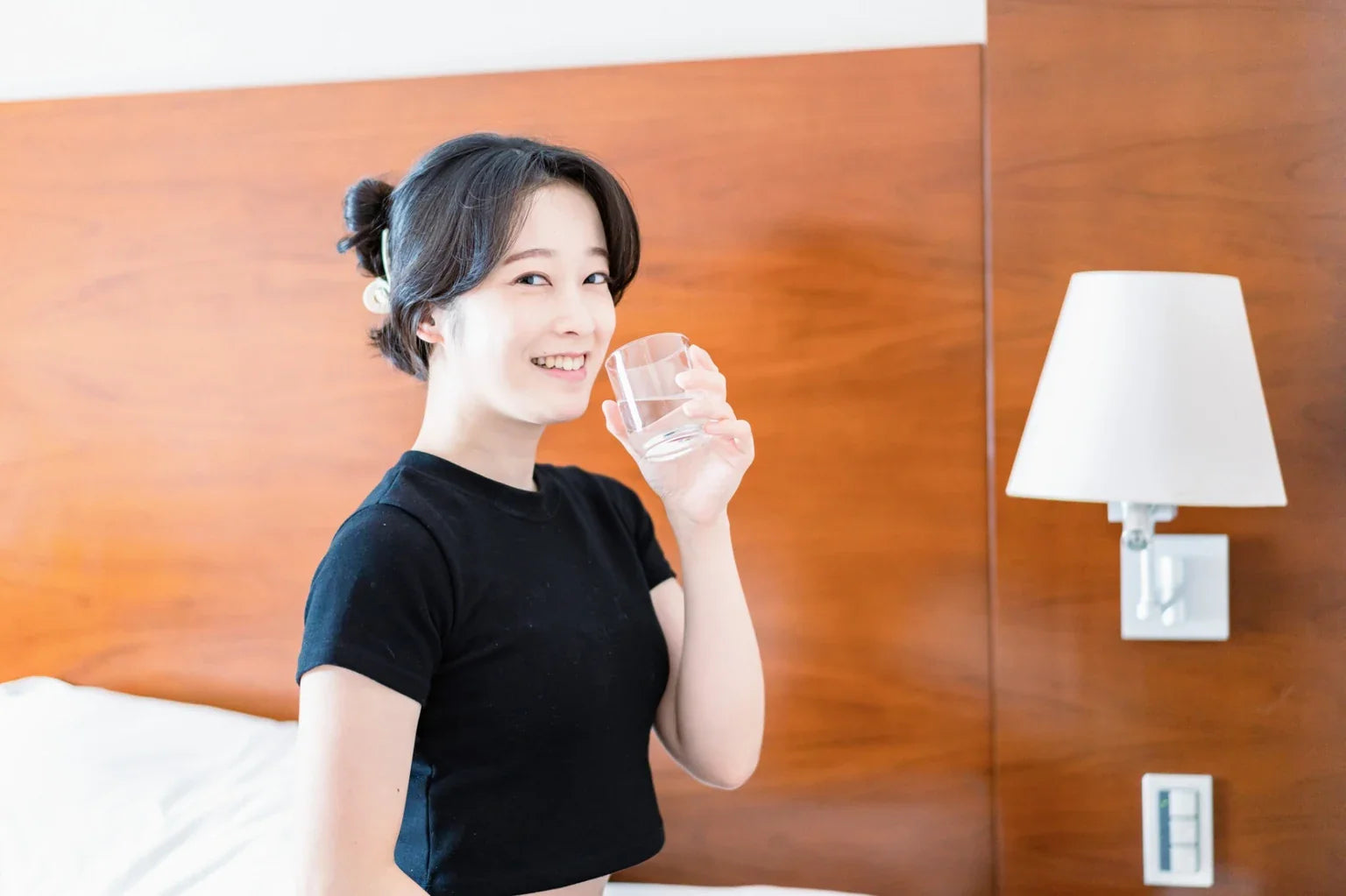 A woman drinking water in the morning, representing a daily hydration habit supported by soft water and a healthy Japanese lifestyle.