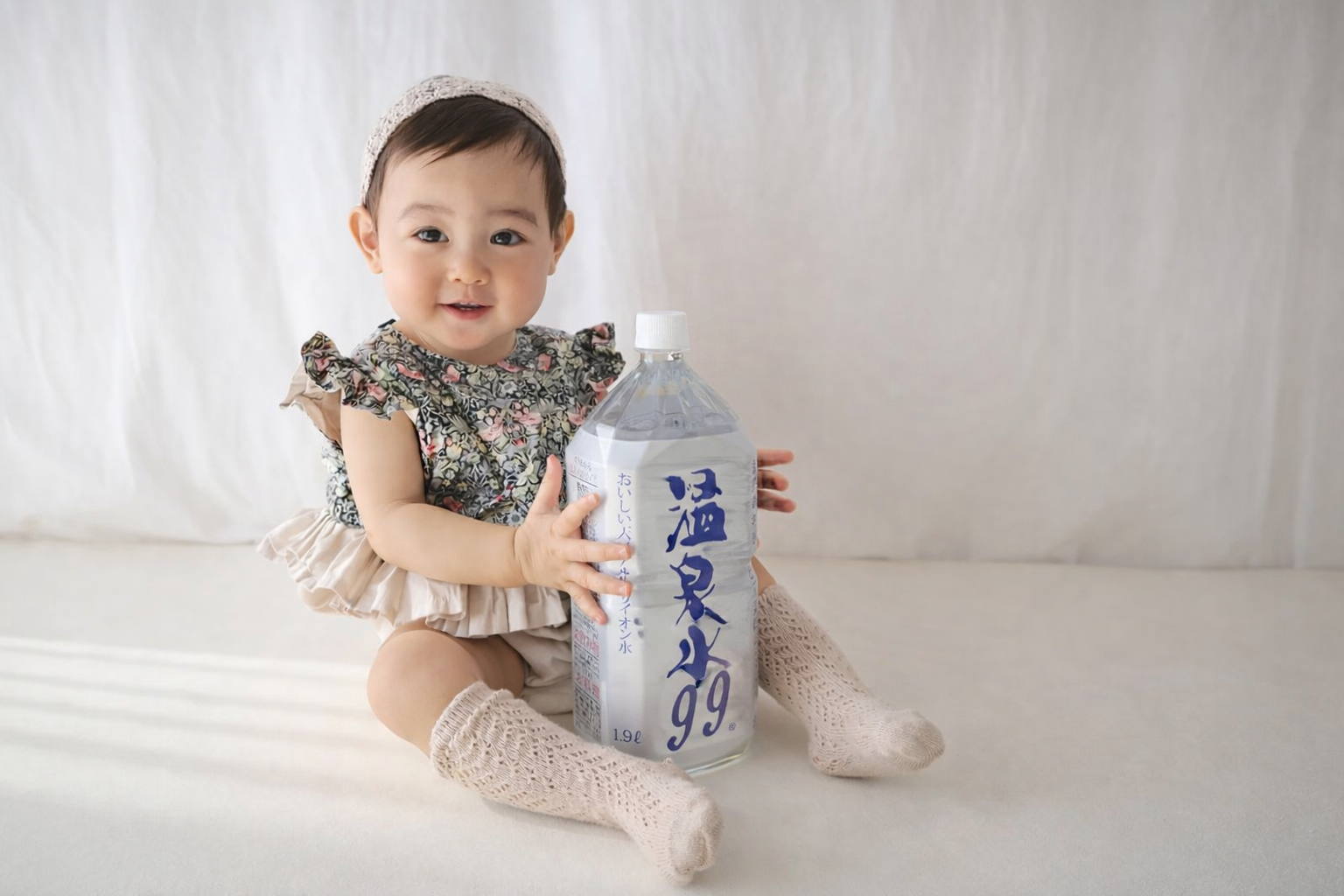 赤ちゃんが温泉水99を抱えてハイチーズ