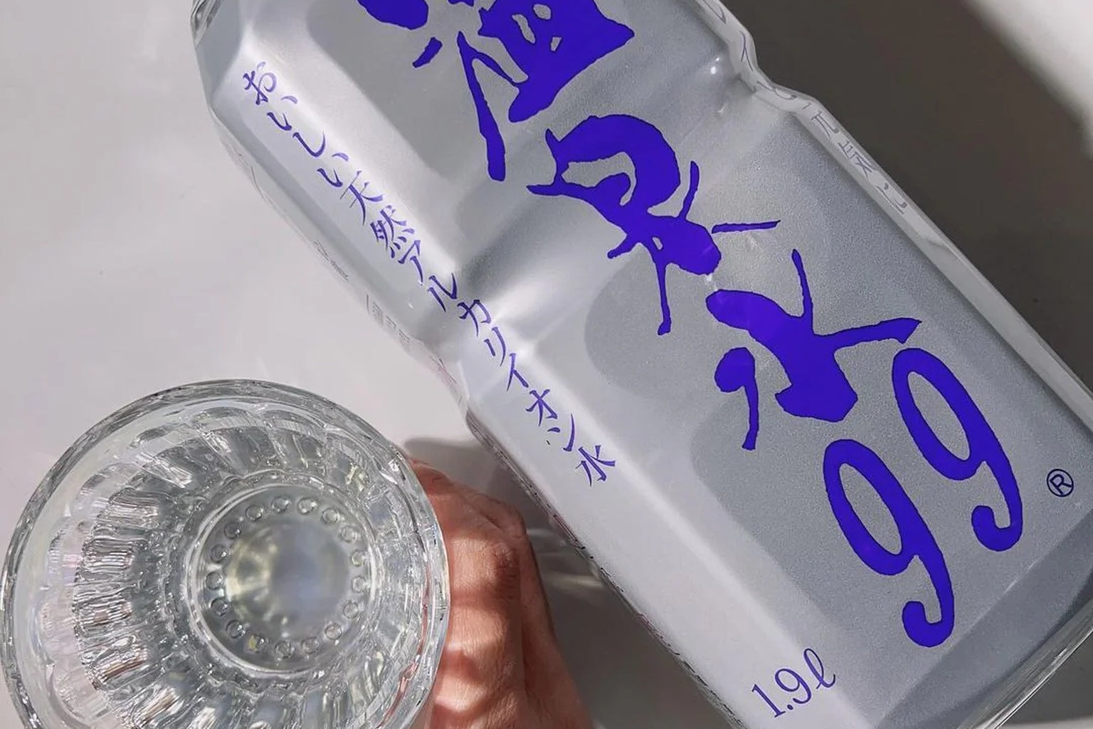 鹿児島・垂水の温泉水99ボトルとグラスを朝日が照らす美容シーン