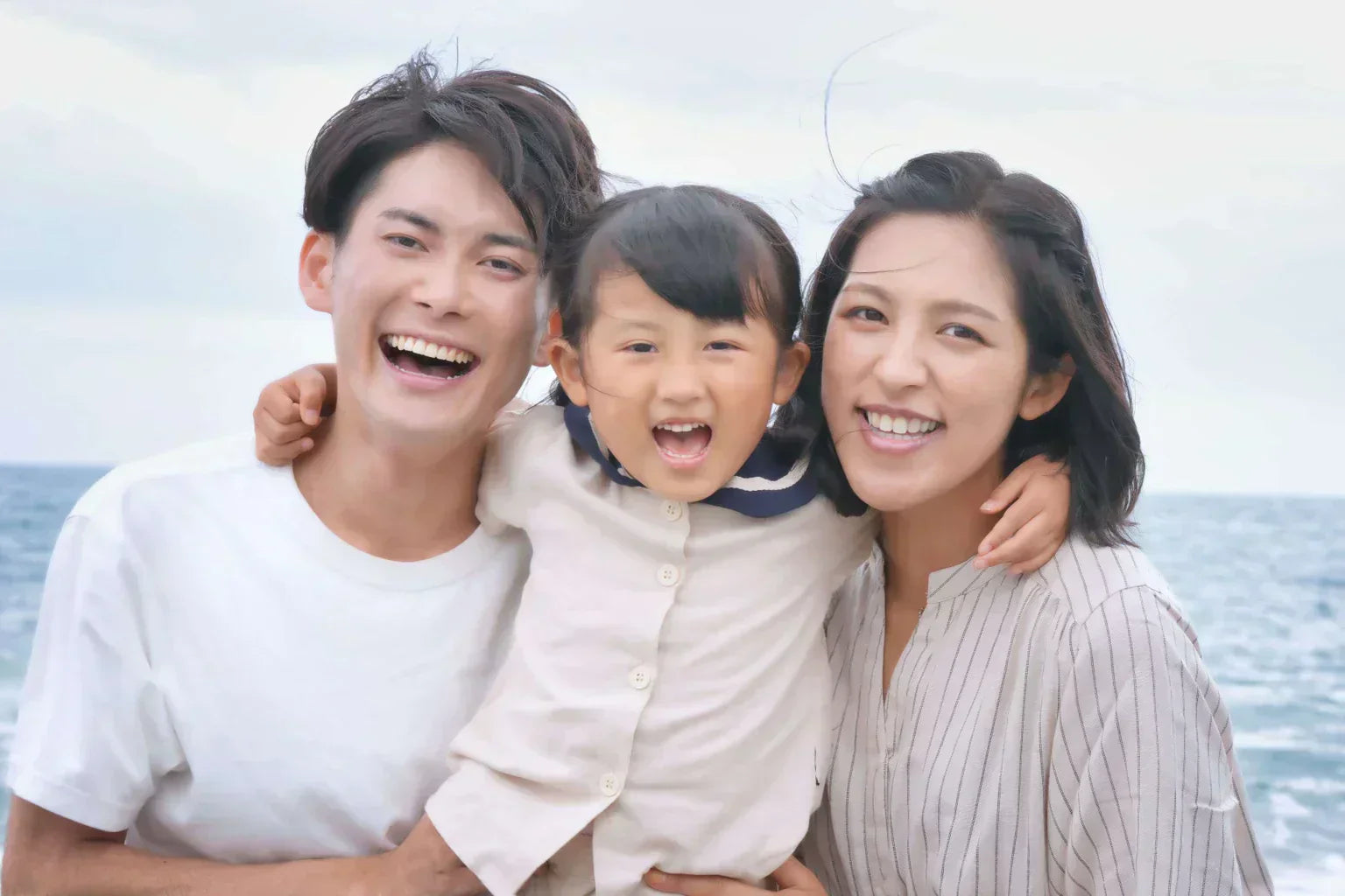Happy family enjoying time together near the ocean for ONSENSUI99 family support campaign