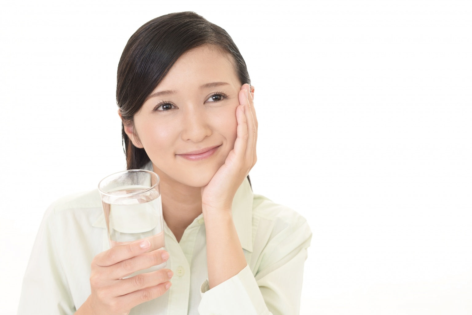 Woman holding a glass of water representing hydration and healthy skin lifestyle