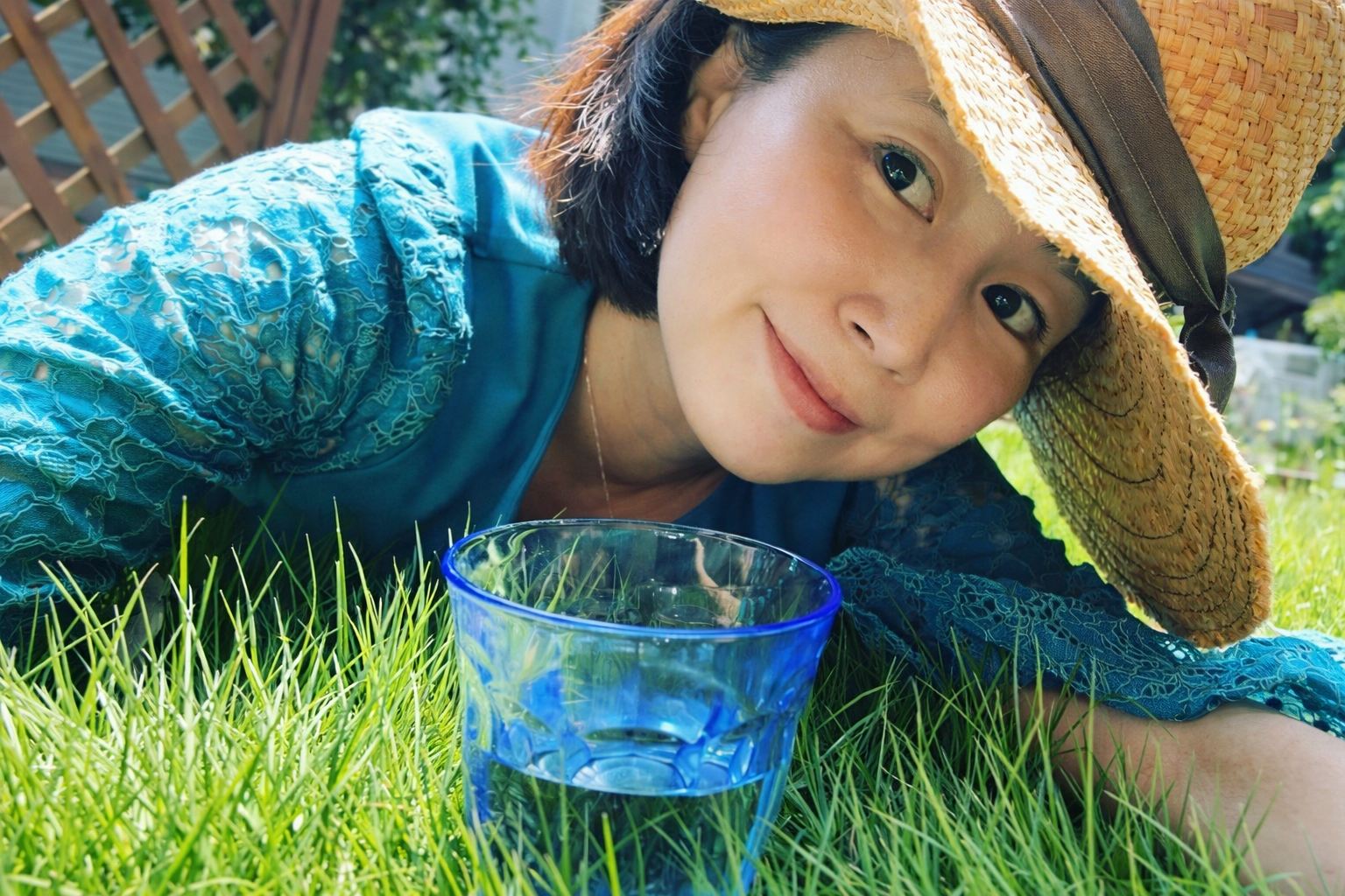 芝生の上でリラックスしながら温泉水99の水を楽しむ女性