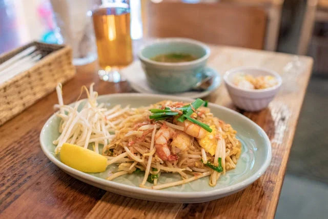 タイのスパイシー料理とグラスの水｜辛い食事の後に身体をやさしく整える“飲む温泉”を象徴