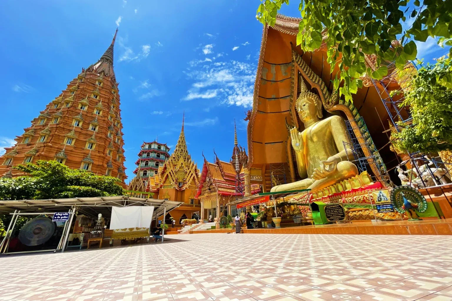 Traditional Thai temple with golden Buddha statue and blue sky in Thailand