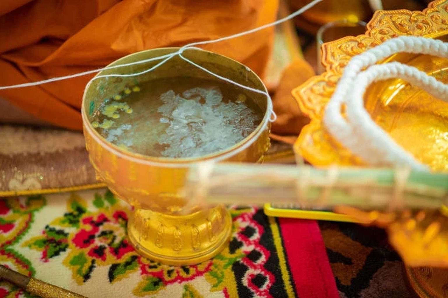 タイの水と信仰。タイの寺院で聖水をかけて祈る僧侶。水による浄化と祝福の儀式